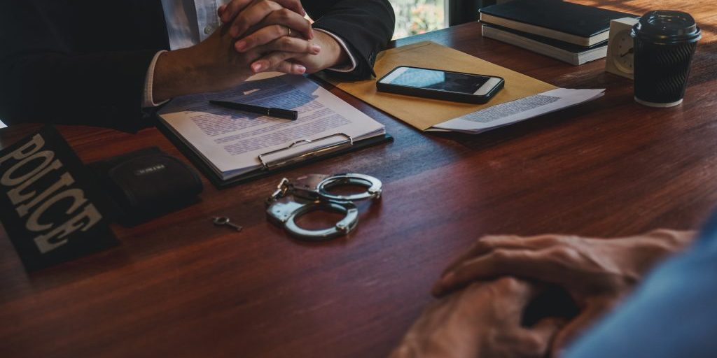 Law enforcement officer interrogating Criminals male with handcuffs in the investigation room Police officer interviewing after committed a crime